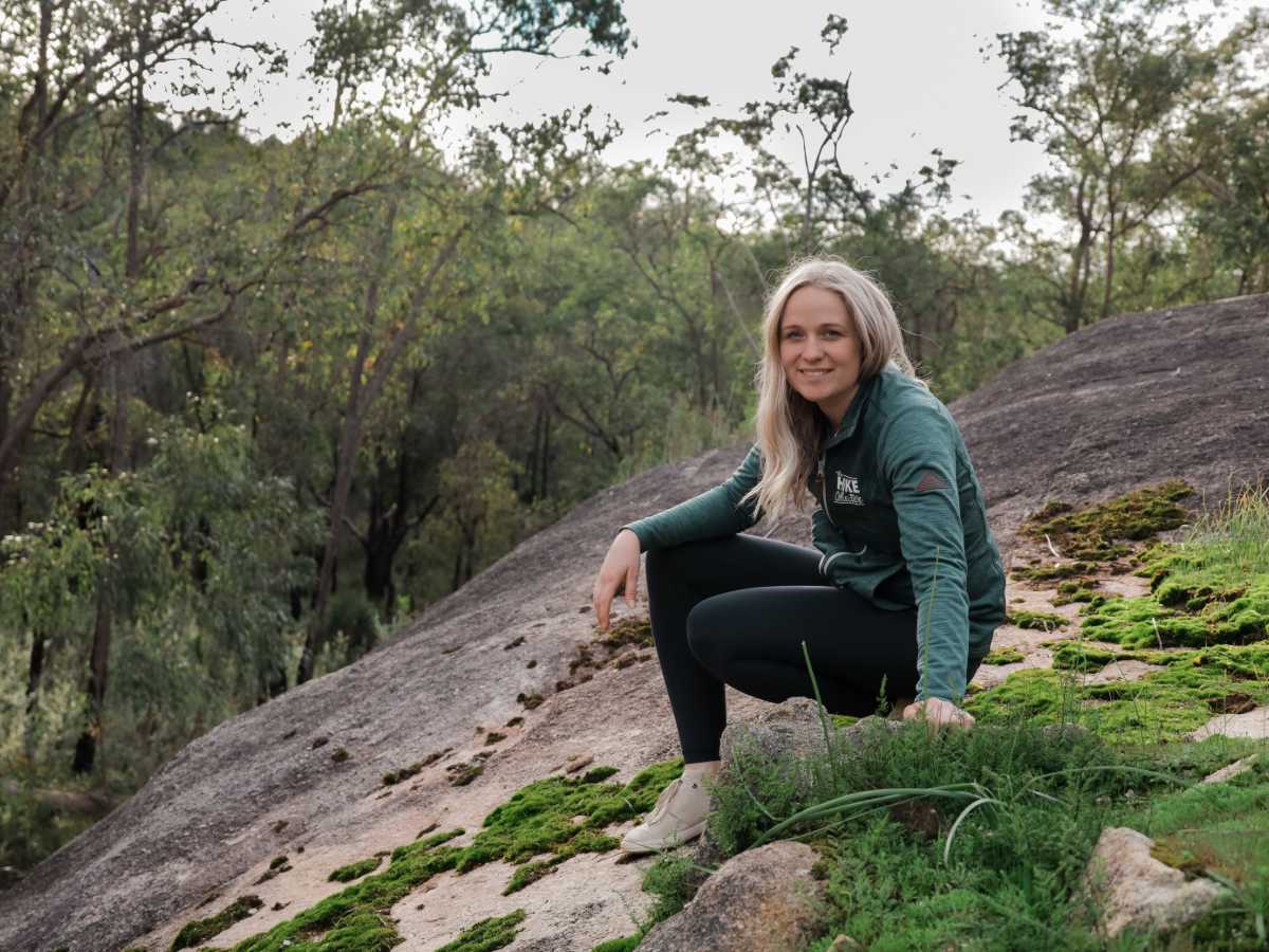 Kate from The Hike Collective on a moss-covered granite trail in Perth Hills