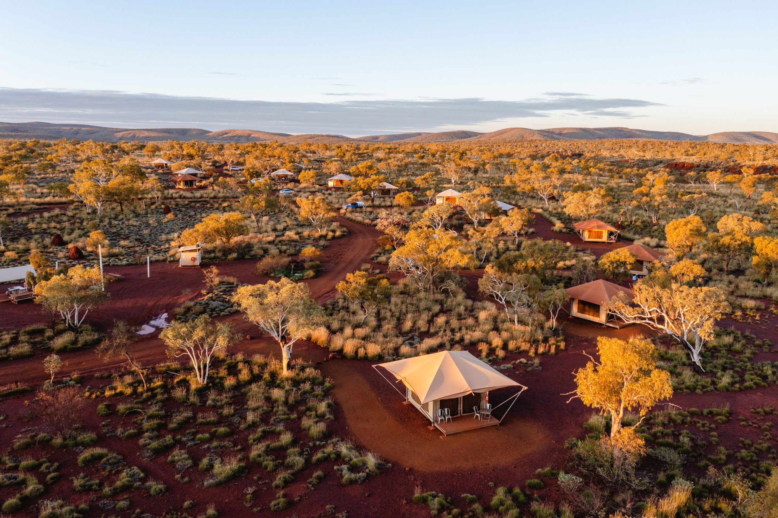 Eco glamping tents nestled in Karijini’s outback landscape at sunset in Western Australia’s Pilbara region