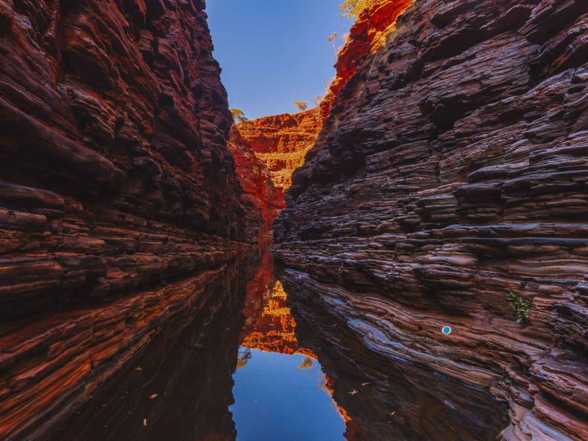 Dramatic red rock gorge reflected in tranquil waters on a Karijini hiking tour in Western Australia